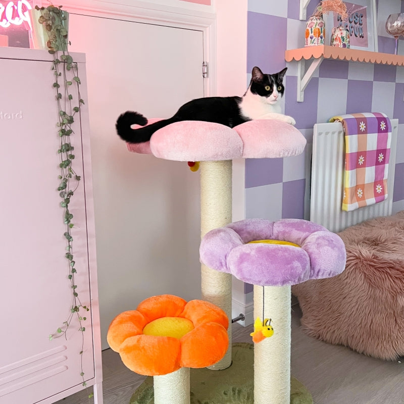 A cat sitting on the flower platform of the Three Flower Cat Tree in a pink-purple themed room